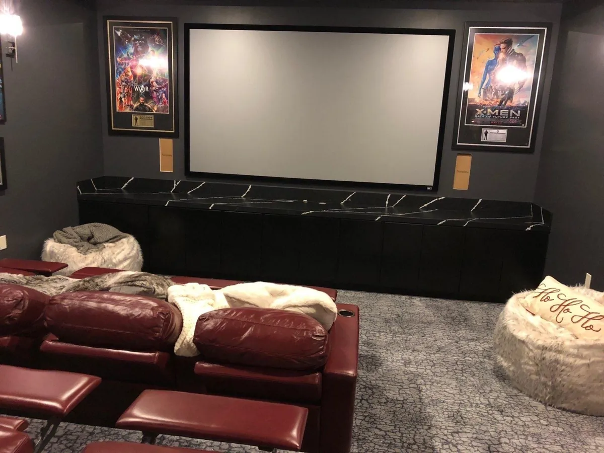 Home theater with a projection screen, framed posters and red leather seating