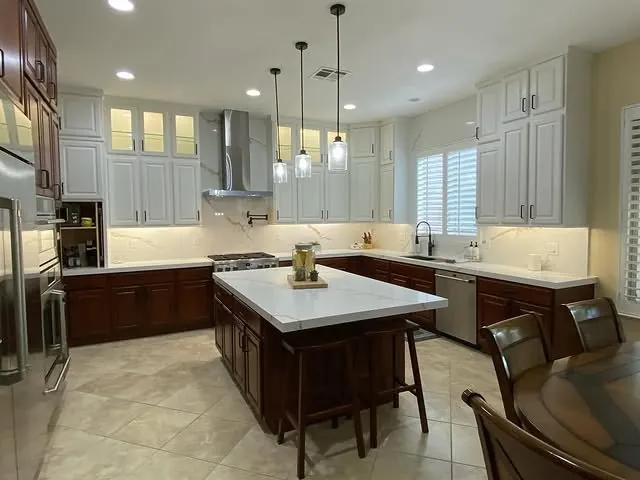 Wide view of the kitchen with glass-front cabinets lit at the top of the 10-foot ceiling