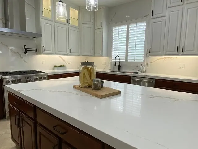 White quartz island and range wall under stacked upper cabinets