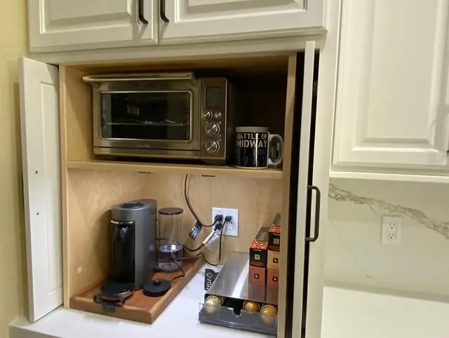 Coffee cubby with the doors open: coffee maker, toaster oven and mugs