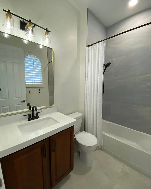 Second bathroom vanity with a framed mirror and a grey feature wall