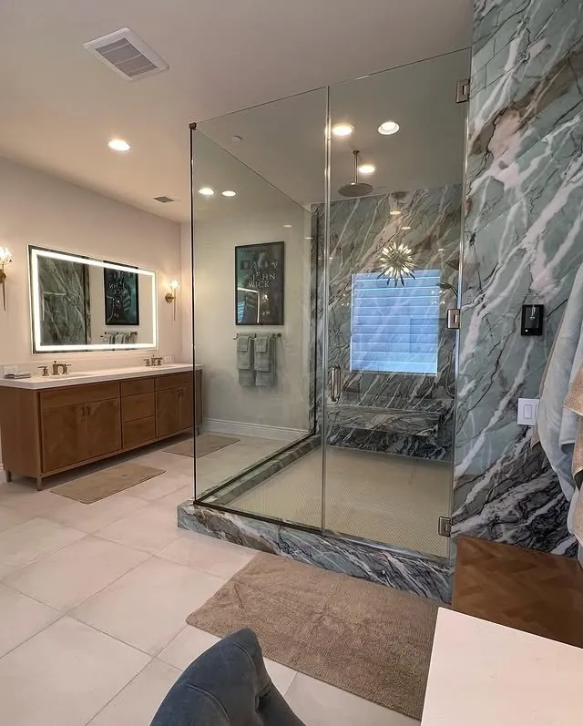 Primary bathroom with a beech vanity and a glass shower with green marble