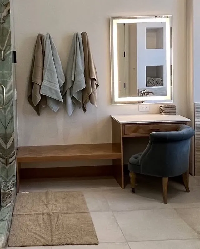 Beech bench and makeup vanity under a lit mirror