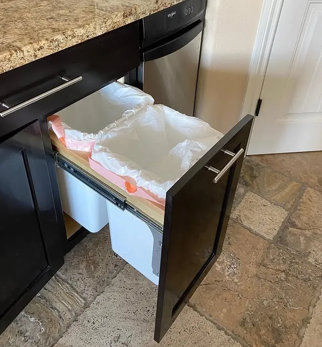 Dark base cabinet with a trash and recycling pull-out opened