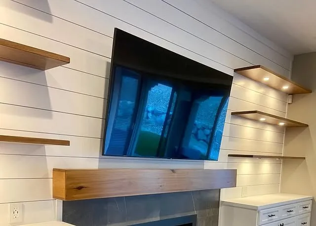Close view of the wood mantel and TV on the shiplap wall