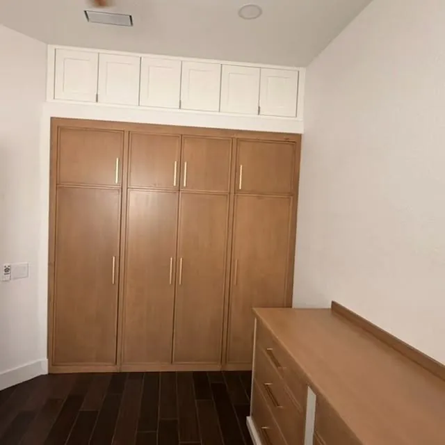 Full-height oak wardrobe wall with brass pulls and a white panelled band above
