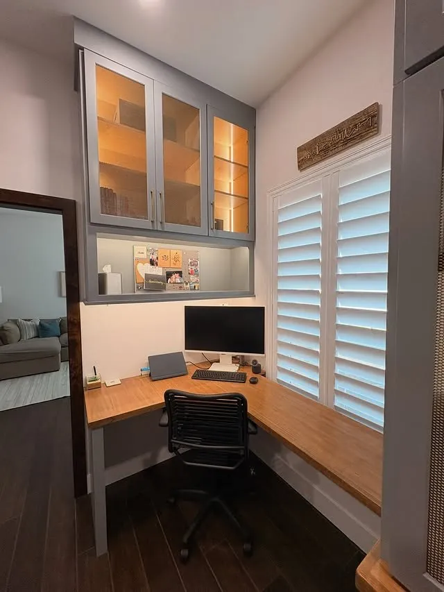 Corner desk under lit glass cabinets