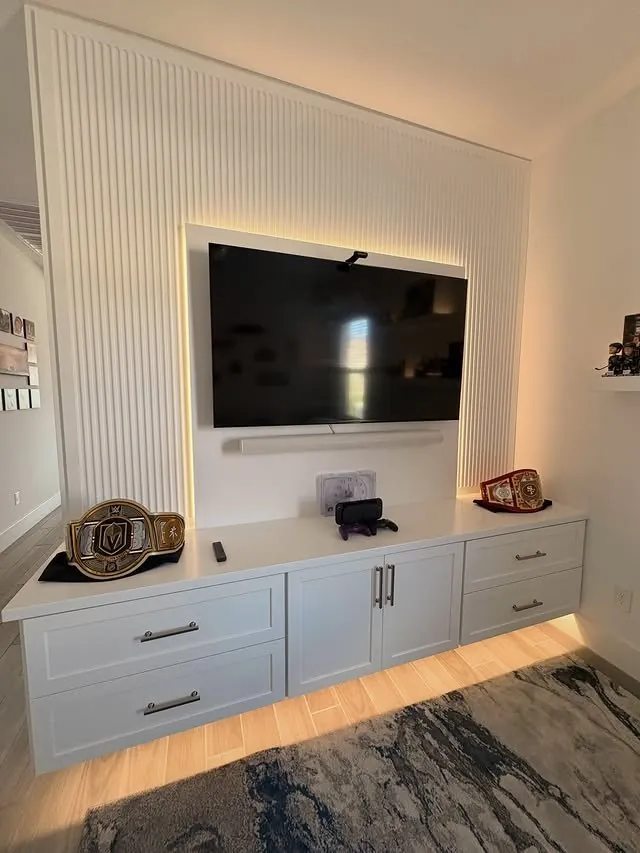 Den media wall with a mounted TV above a white floating cabinet