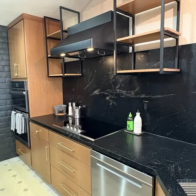 Black granite backsplash and counter under a custom metal range hood