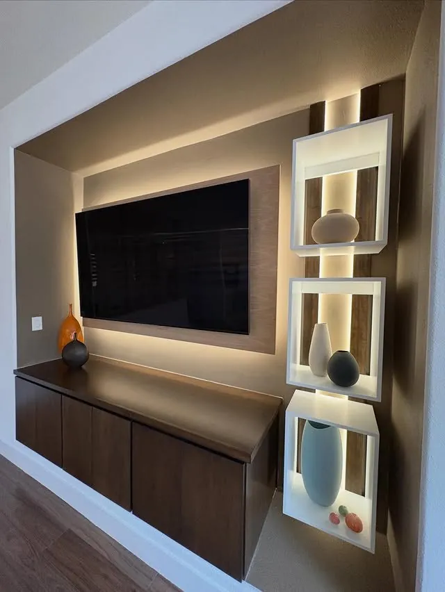 Backlit media wall with a dark floating cabinet and lit white display niches