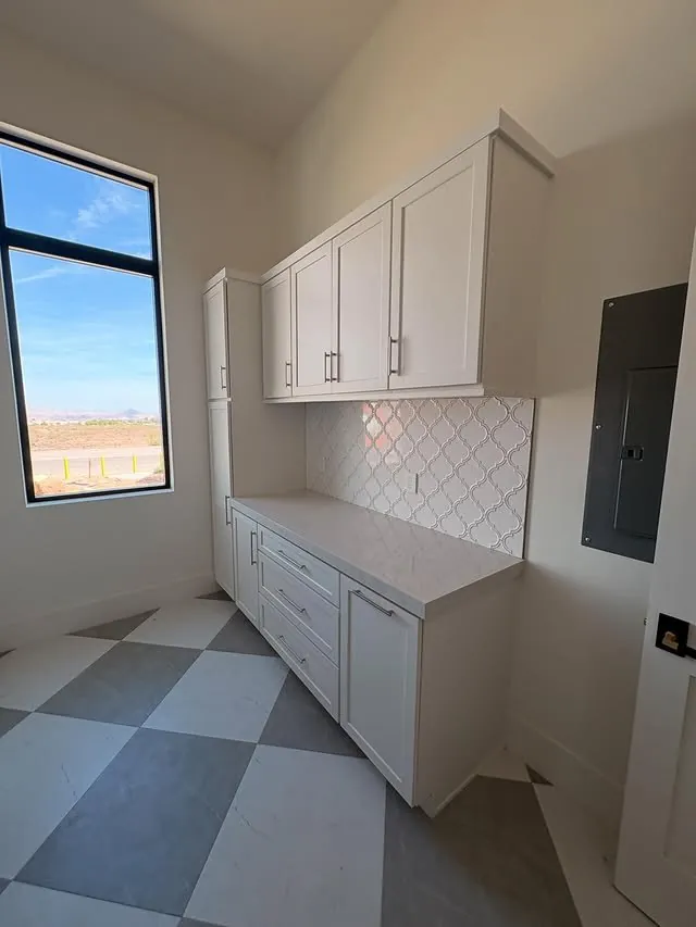 L-shaped white laundry cabinets with a folding counter and a checkerboard floor