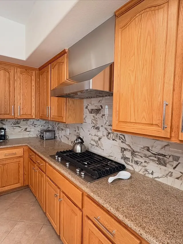Wider view of the oak kitchen with the new hood surround above the cooktop
