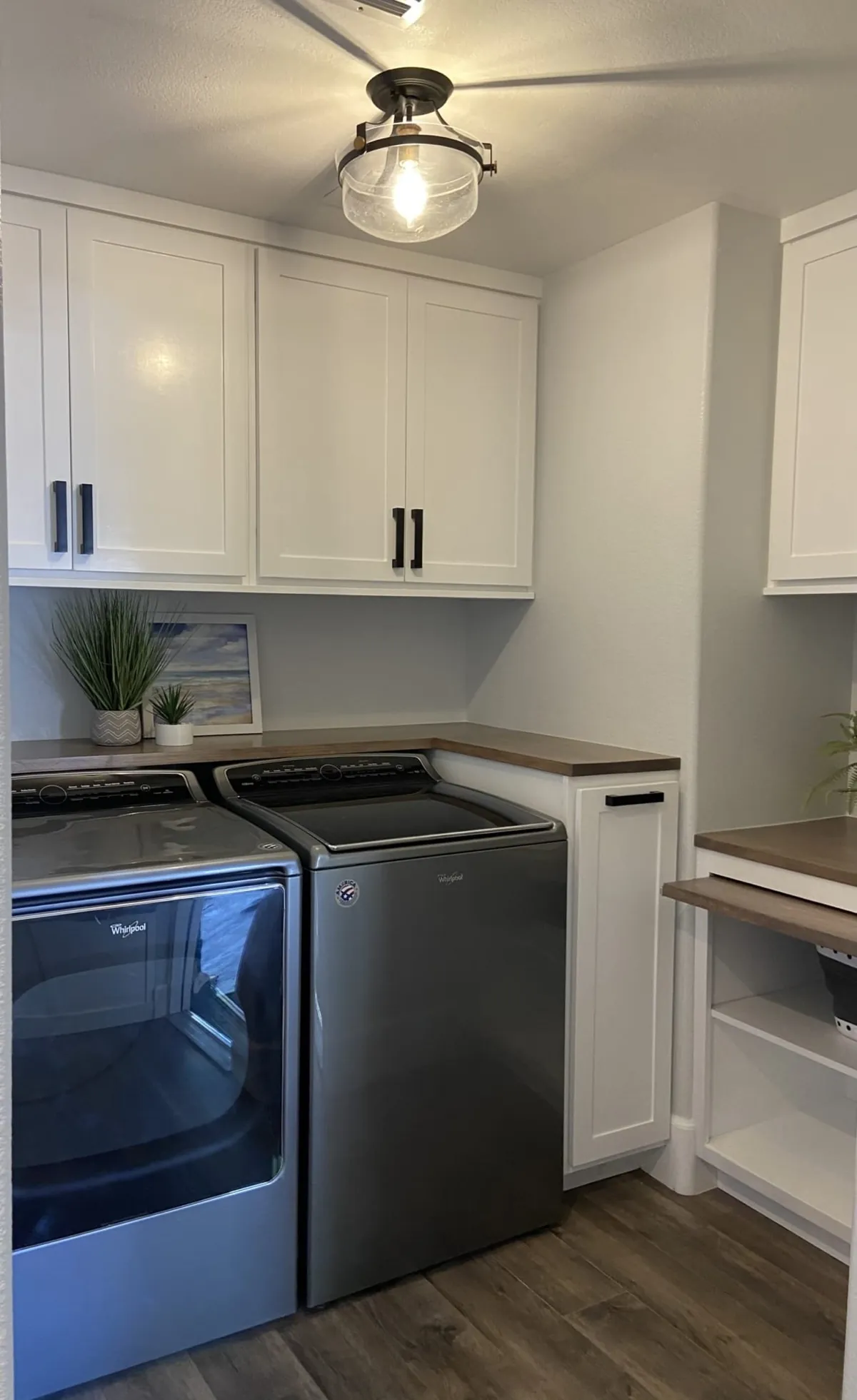 Laundry room with white cabinets and a pull-out beside the washer and dryer
