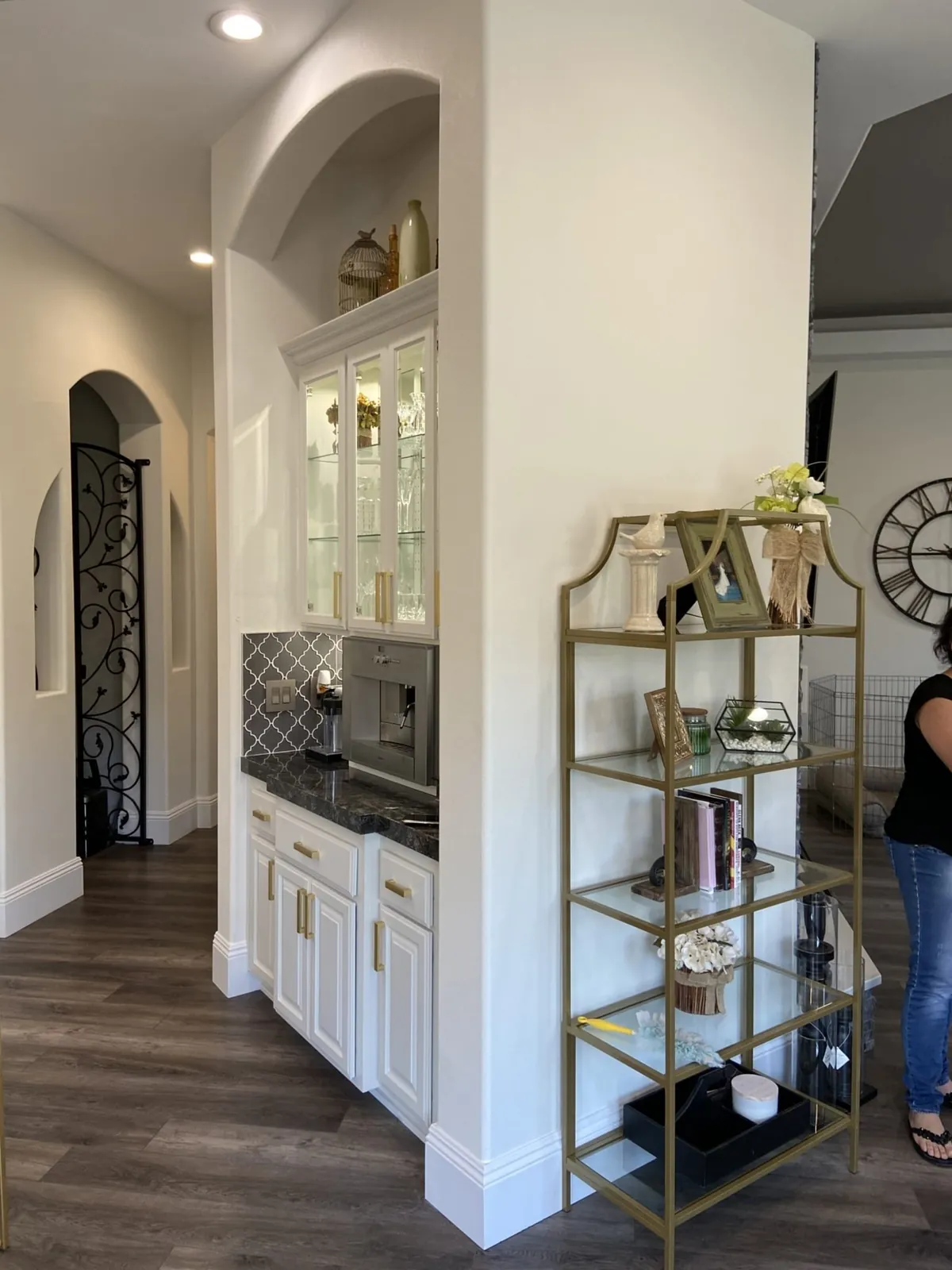 White glass-front cabinet and a brass etagere by the kitchen doorway