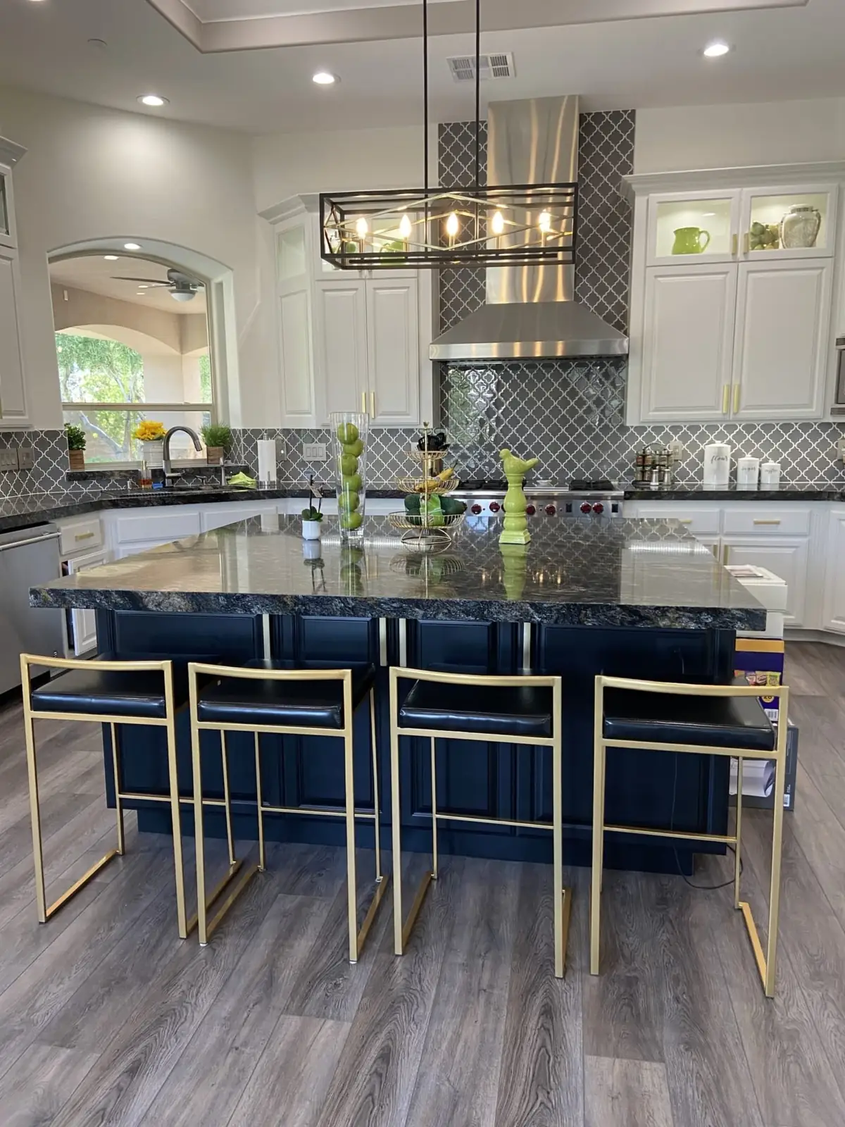 Kitchen with a navy island, granite top and brass-framed bar stools