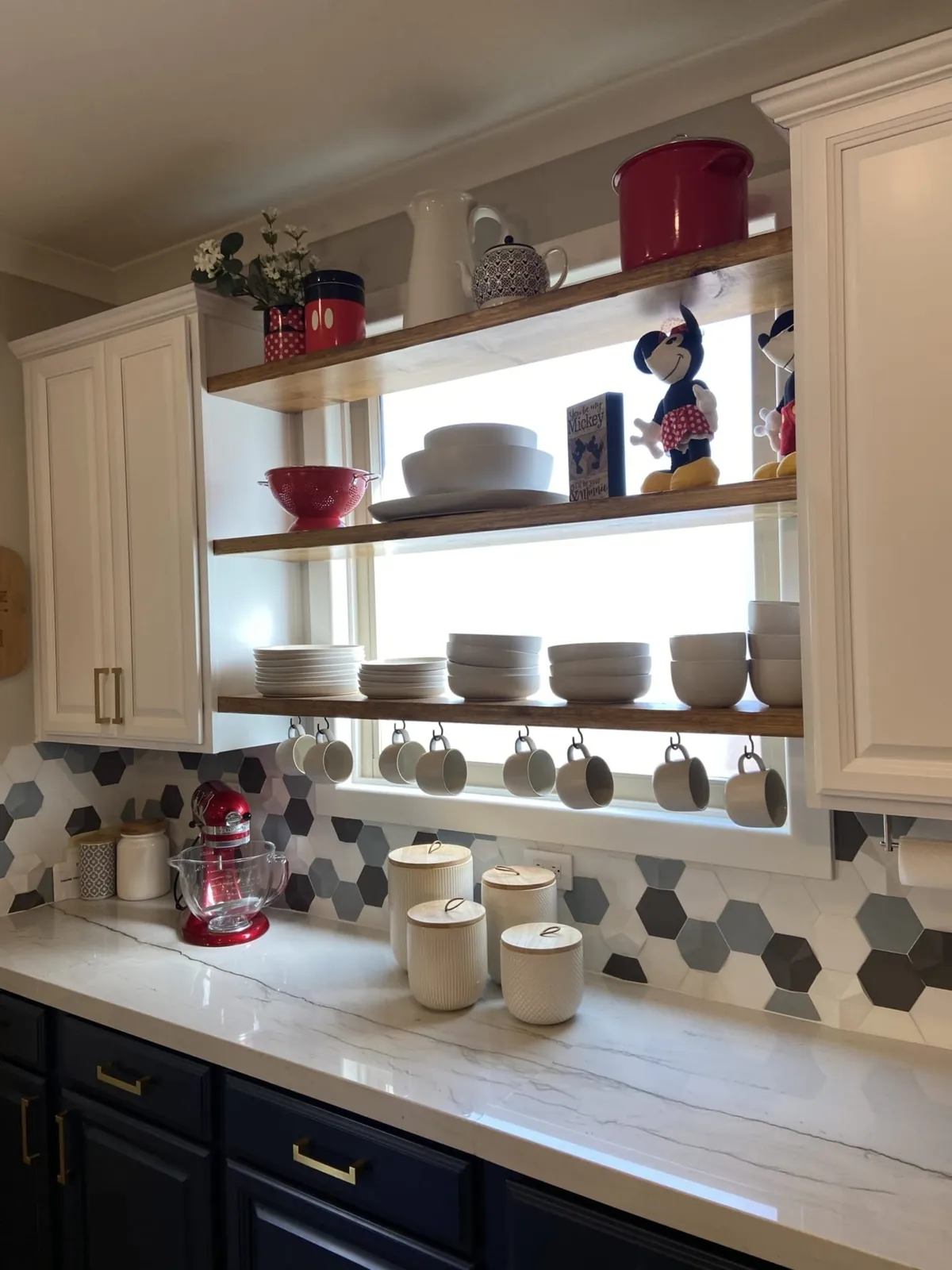 Open wood shelves with dishes over navy base cabinets and hex tile